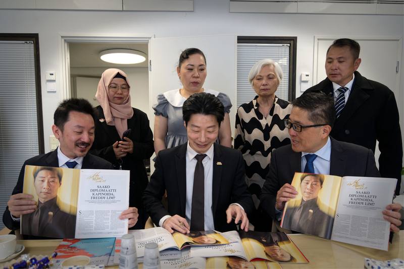 駐芬蘭代表林昶佐（前中）贈台商刊登其專訪的百年政經雜誌「芬蘭畫報」，並以老派鋼筆逐一簽名。