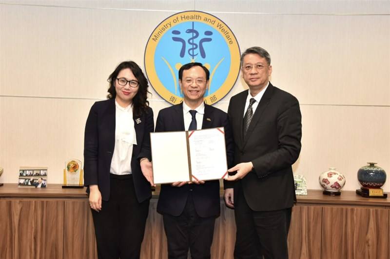 Health and Welfare Minister Shih Chung-liang (center) holds a partnership agreement with the United Kingdom's National Institute for Health and Care Excellence, signed by National Health Insurance Administration Director-General Chen Lian-Yu (left). Photo
