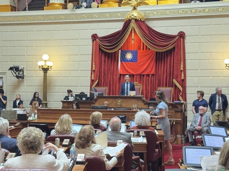 美國羅德島州議院12日通過友台決議，會場高掛中華民國國旗，駐波士頓辦事處長廖朝宏在主席台上感謝州議員長期對台支持。（駐波士頓辦事處提供）