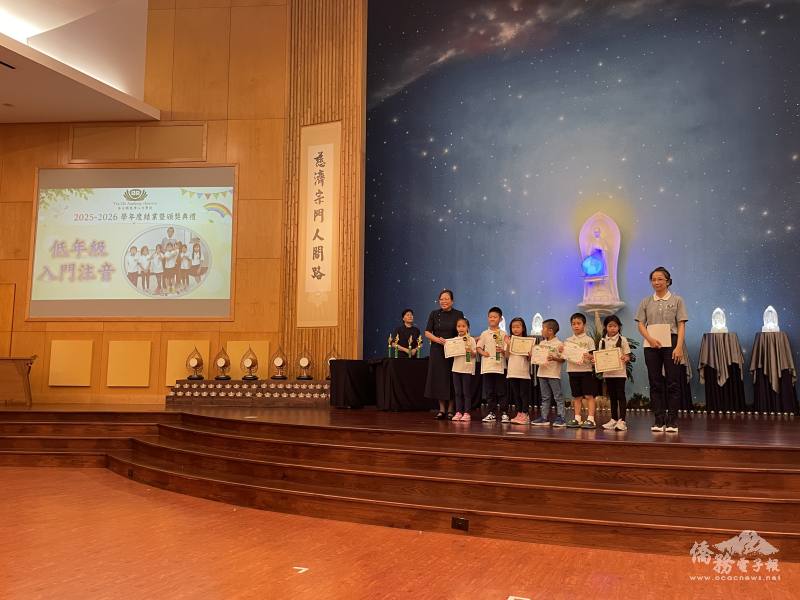 曾維真(左)為低年級入門注音班同學頒獎