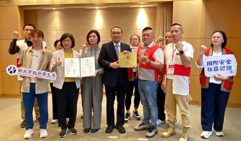 新北市烏來區4月18日被認證為國際安全社區，市府原住民族行政局長Siku Yaway林瑋茜（前左3）、衛生局長陳潤秋（前左2），20日偕同烏來衛生促進會理事長林東暭（前右2）及團隊、區長周至剛（前右3），在市政會議分享喜悅並與市長侯友宜（前中）合影。