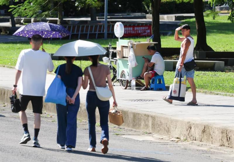 中央氣象署26日針對台北市發布可能出現38度極端高溫的橙色燈號。圖為台北華山大草原周邊午後民眾撐傘遮陽。