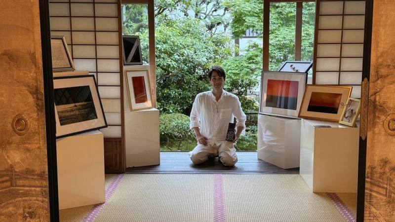 以「色彩」為題的Colors特展27日起在日本京都泉涌寺登場，展覽集結台灣藝術家蔡爾平、長年在京都創作的台灣陶藝家張義明，以及旅居台灣的日本攝影藝術家岡本孝3人作品，透過陶藝、攝影與複合媒材等不同形式，共同詮釋人與自然之間的色彩語言。圖為岡本孝與作品合影。（台灣國王十字藝術社提供）