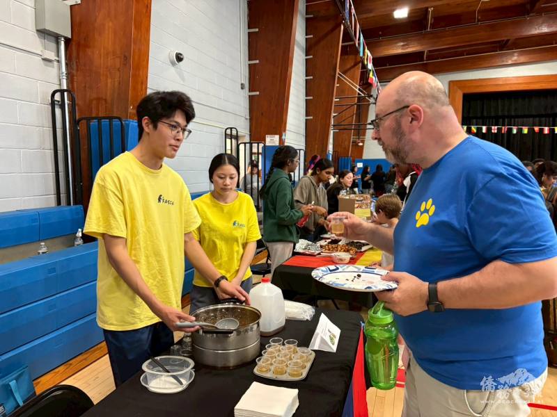 An Albany FASCA student offers aiyu drink to a local attendee, sharing a moment of cultural connection.