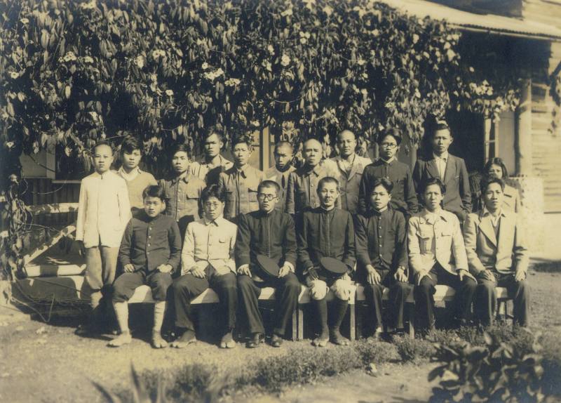 1943年正月魚池紅茶試驗支所全體員工紀念照。圖中前排中央者為支所長新井耕吉郎。其穿著黑色夾腳膠鞋、紮綁腿，彷彿拍照後即將前往茶園。前試驗所員工竹下貝提供