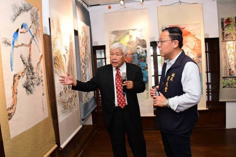 新禾文化藝術協會藝術下鄉2026年首展在台東縣關山鎮藝文中心揭幕，自即日起展出至28日，協會理事長賴世榮（左）為關山鎮長彭成豐（右）介紹展示作品。（賴世榮提供）