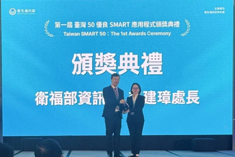 衛生福利部主辦第1屆台灣50優良SMART應用程式競賽，日前舉行頒獎典禮，衛福部資訊處長李建璋（左）親自頒發獎盃，慧德科技總經理李慧鈴（右）受獎。（慧德科技提供）