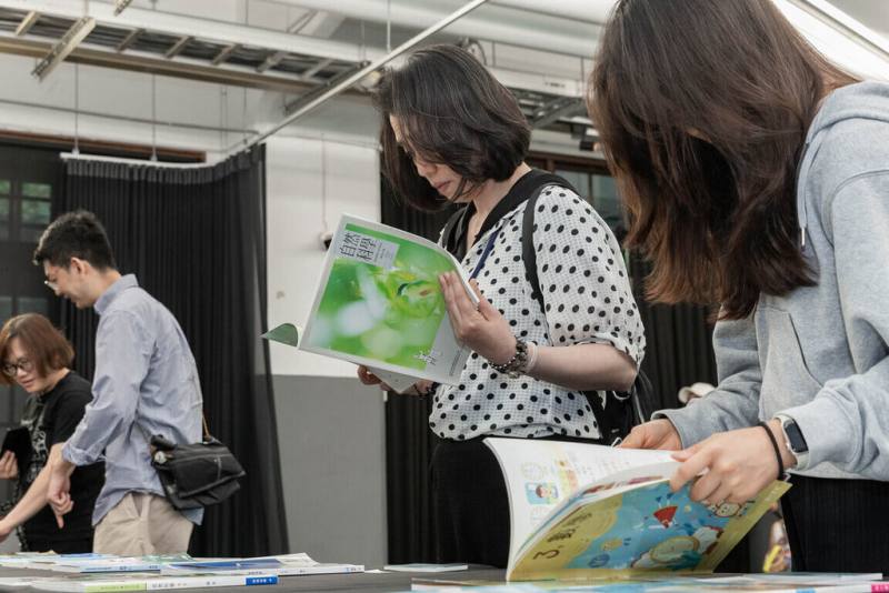 台灣設計研究院日前舉辦「教育新視野：翻轉教材實踐論壇」，並設置成果展區，展出教科書設計獎獲獎作品及教科書創新設計補助計畫獲選作品。圖為民眾於展區翻閱補助案改造成果情形。（台灣設計研究院提供）