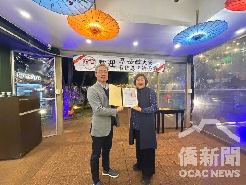 李岳融(左)代表僑務委員會頒贈榮譽職聘書予僑務促進委員周秀香