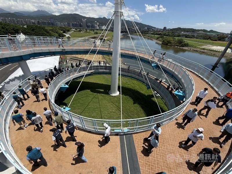 People walk along the circular steel ramp of the newly opened elevated pedestrian walkway connected to Minquan Bridge along the Keelung River in Taipei on Monday.