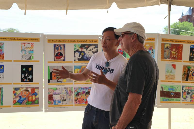 代表處職員向參觀民眾介紹展出的臺中市政府「全國兒童聯想畫創作比賽」作品。