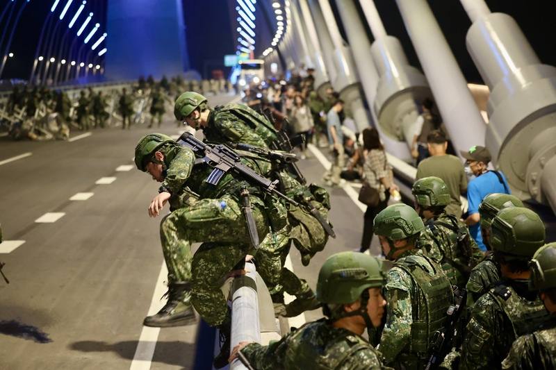 Sappers climb over the railing of the Danjiang Bridge during a defensive blockade drill in New Taipei late Thursday.