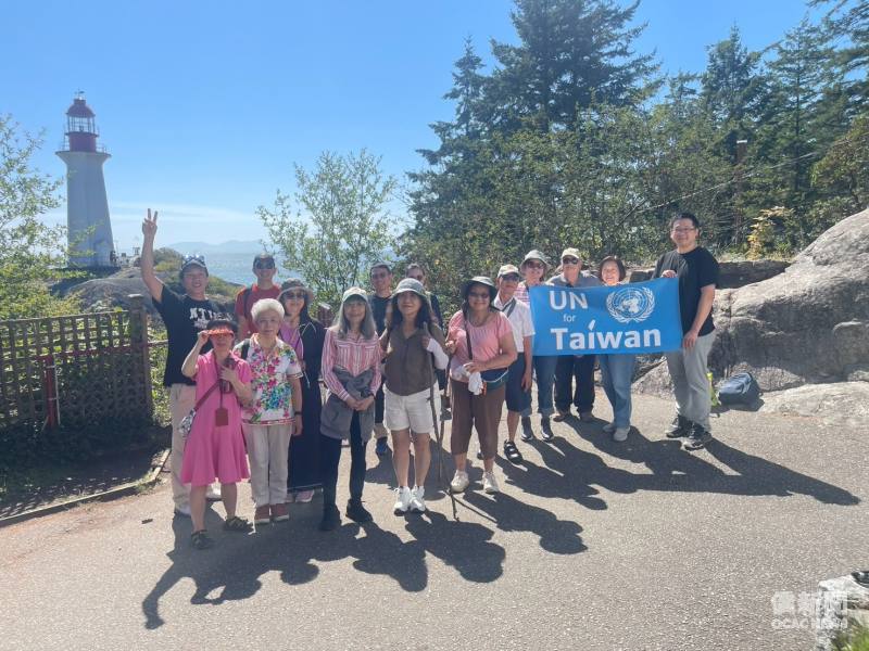 參與秋季健行活動的校友及僑胞於燈塔景點合影，並展示「UN for Taiwan」標語，展現支持臺灣國際參與的熱忱。