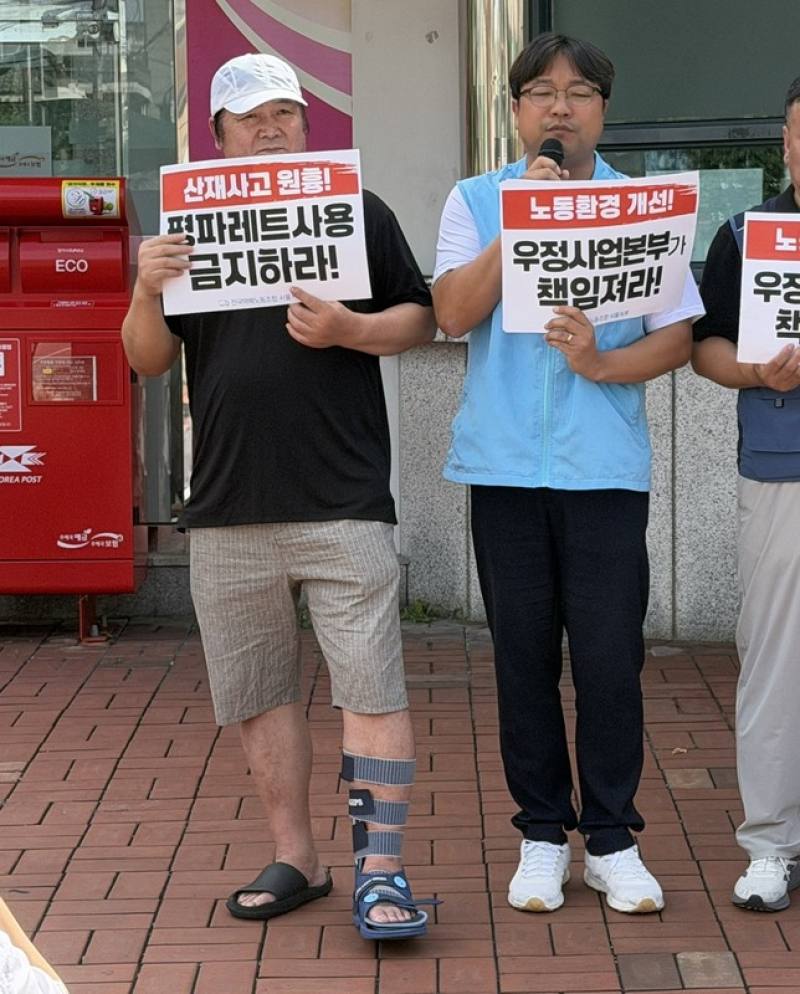 韓國民主勞總全國宅配工會10日在東首爾郵件集中局前示威，在分類作業中腳背骨折的快遞員朴泰宇（左）10日帶傷出席記者會，腳部仍穿著護具。