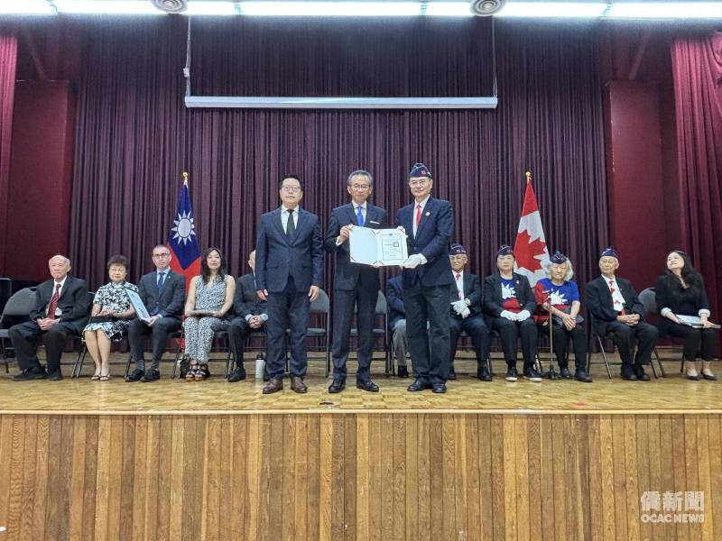梁毅鵬(中立者)頒發僑務委員會委員長徐佳青賀狀予新任理事長賴道翁（立者右1）。