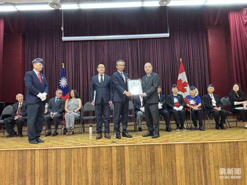 駐多倫多辦事處處長梁毅鵬（立者右2）頒發頒發國軍退除役官兵輔導委員會感謝狀予潘桂興，由其長子潘居仁（立者右1）代為接受。