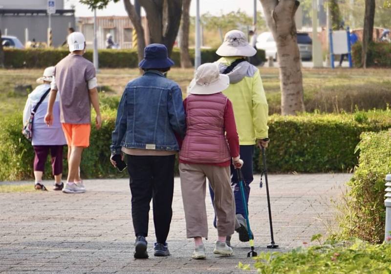 圖為高雄市鳳山區多名拄著拐杖的長者在公園內健走散步。