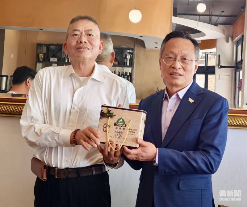 卓銘德（左）代表阿彌陀佛關懷中心創辦人慧禮法師，致贈菩提園橄欖油予廖文哲。