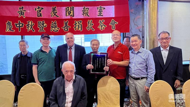 波士頓台山鄉親聯誼會會長黃紹培（立者右三）和該會幹部送上牌匾給黃官羨（立者中）。