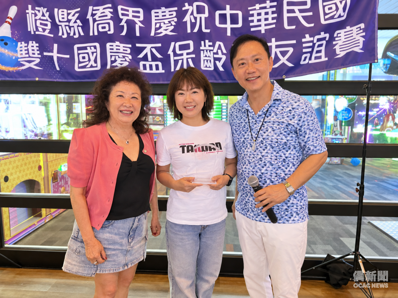 橙僑中心主任蕭蓓如（中）獲頒女子亞軍獎盃 ，僑務諮詢委員林翠雲（左）及黃建誠致賀