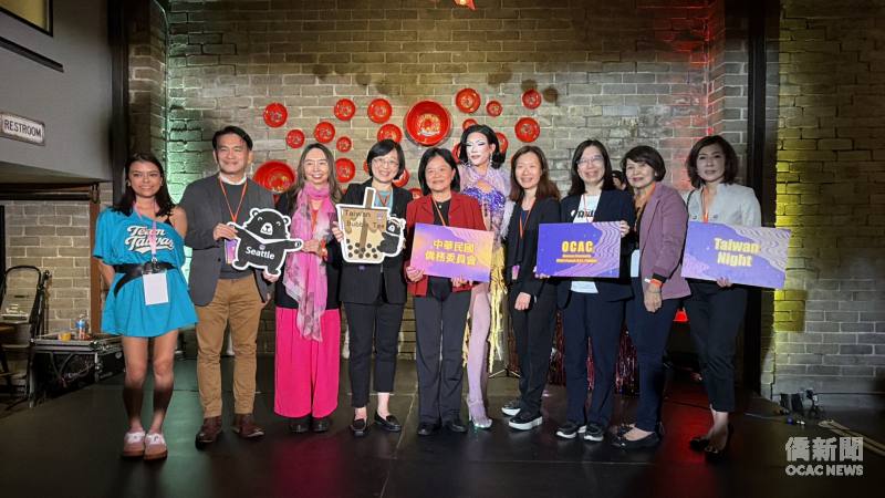 貴賓與表演者於「Taiwan Night臺灣之夜」活動現場合影，手持OCAC及Taiwan Night等手牌，展現活動熱鬧多元的氣氛。