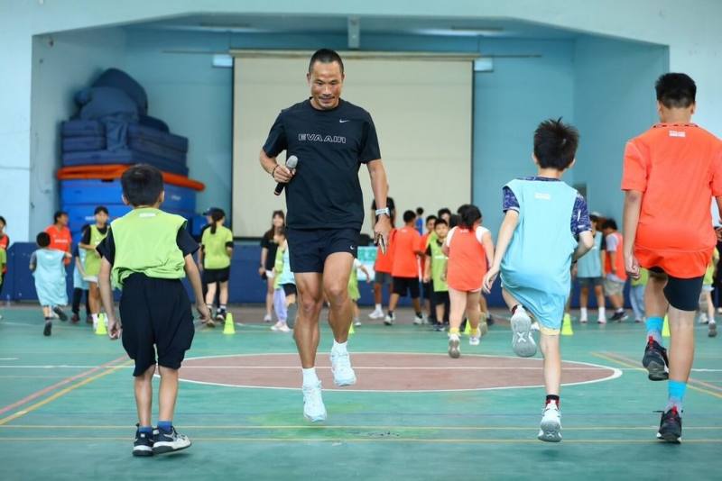 2026長榮航空馬拉松「幼苗計畫－校園深耕巡迴」今年共有2場，9月前進苗栗，奧運馬拉松國手吳文騫（持麥克風者）親自指導百名偏鄉學生，透過互動課程提升學生對運動的興趣。（長榮航空提供）