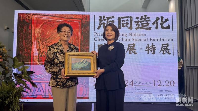 「版同造化－陳國展特展」24日在屏東縣立美術館開展，已故版畫蝕刻大師陳國展妻子李玉鳳（左）感謝用心規劃，並贈陳國展「玉山之美」作品給屏東縣長周春米（右）。