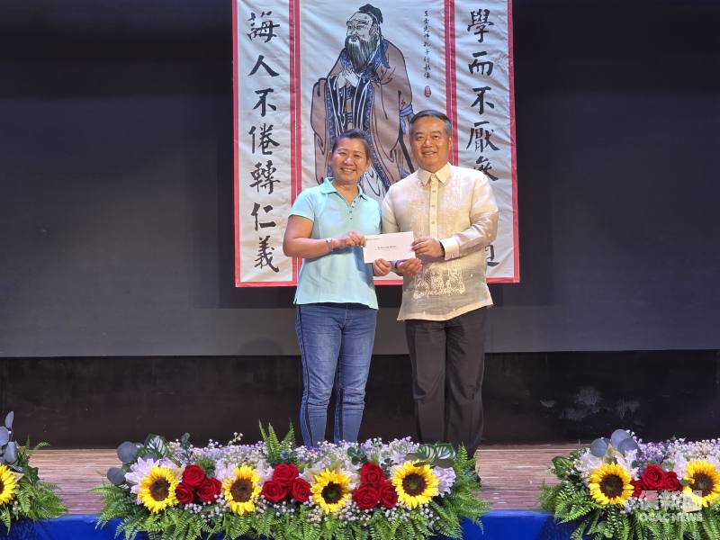 周民淦（右）頒贈由僑務委員會委員長徐佳青提供的「馬尼拉－臺北」來回機票予摸彩幸運得主計順市菲華中學老師葉欣蓮(左)。
