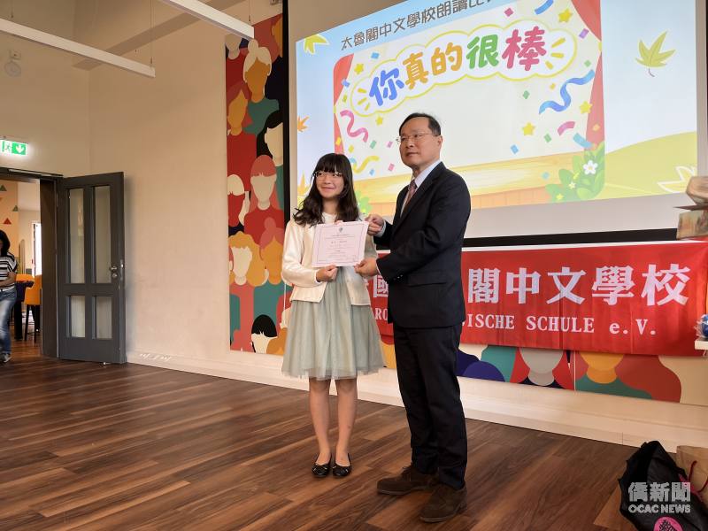 駐法蘭克福辦事處僑務參事林宏穎頒獎表揚朗讀比賽獲獎學生。