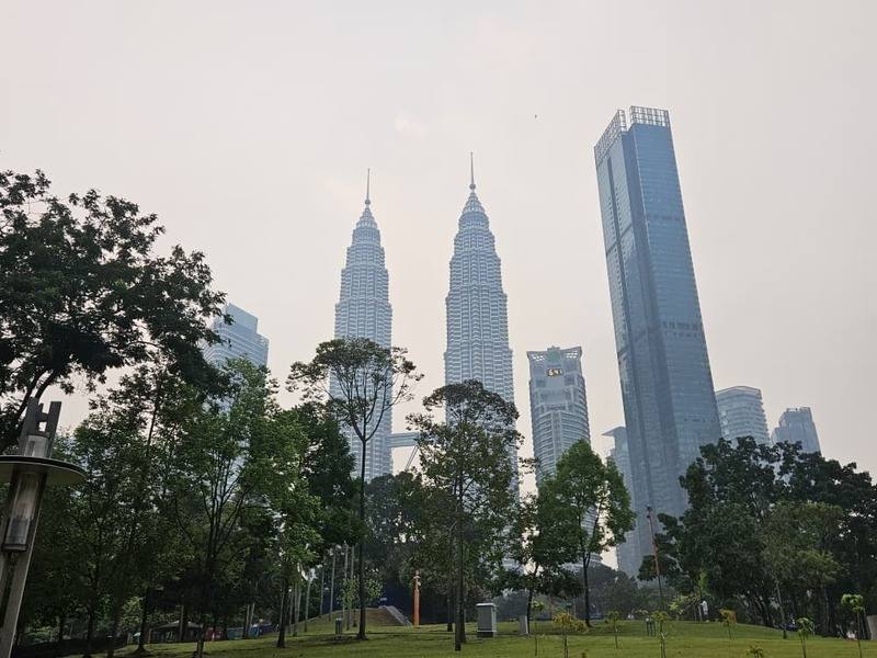 跨境煙霾持續影響馬來西亞，吉隆坡地標國油雙峰塔及周邊高樓19日籠罩在灰濛濛的天空下。大馬政府將充分提供人造雨作業所需經費，盼減輕霾害。